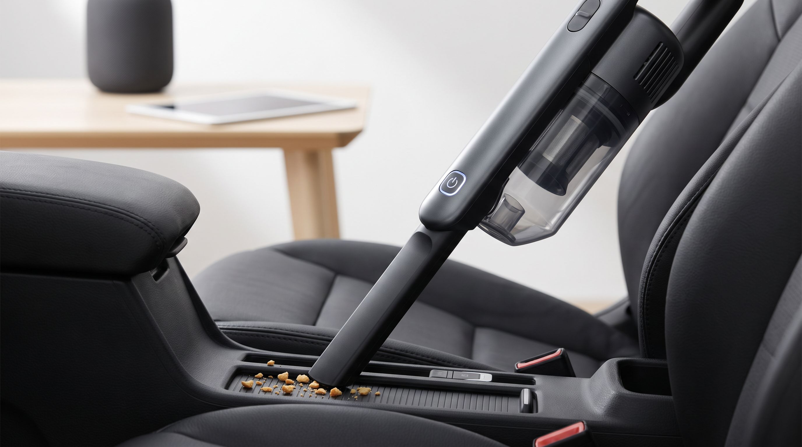 A cordless handheld vacuum with a crevice tool attached, cleaning crumbs from between a car's front seat and center console