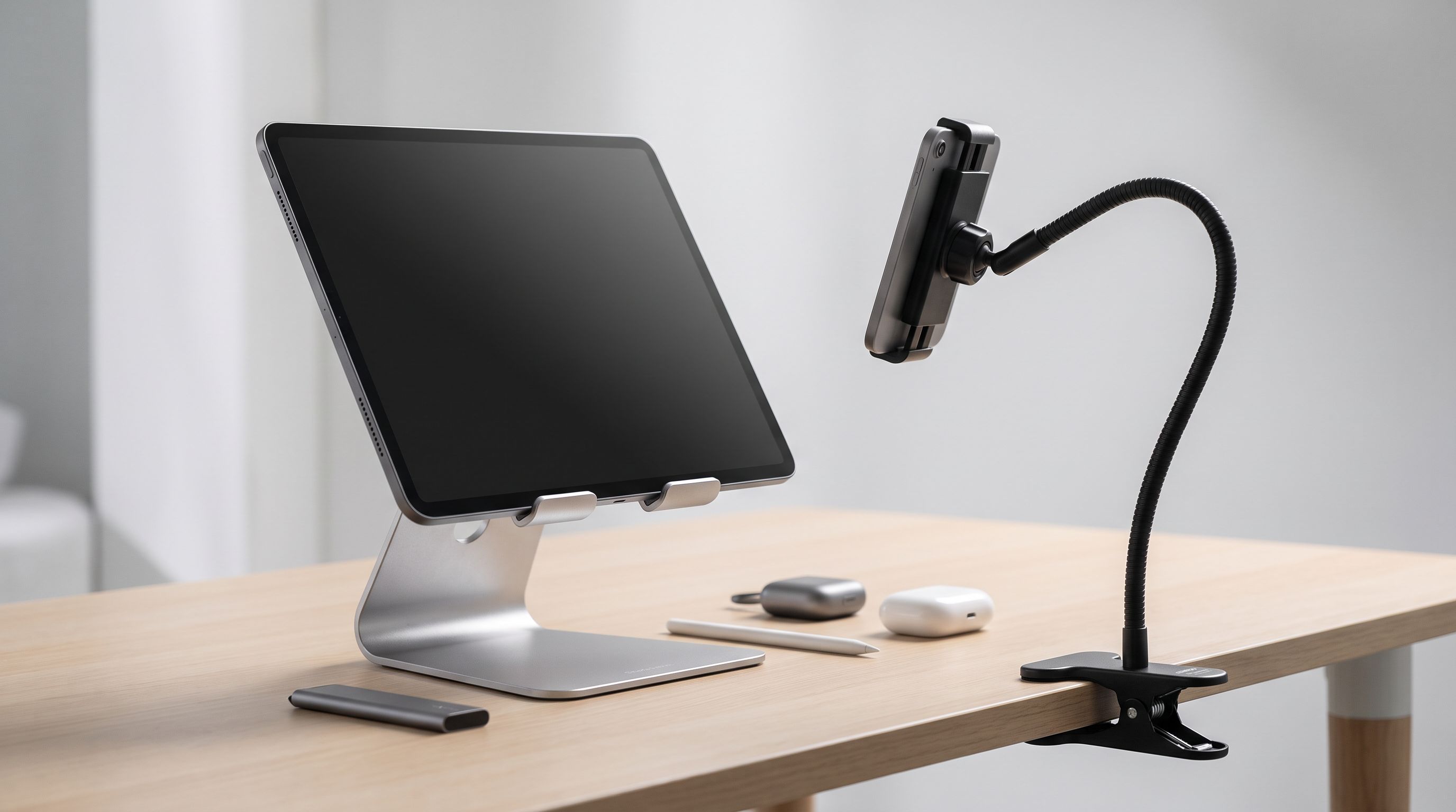 An aluminium adjustable tablet stand holding a large tablet on a wooden desk, next to a gooseneck bedside holder