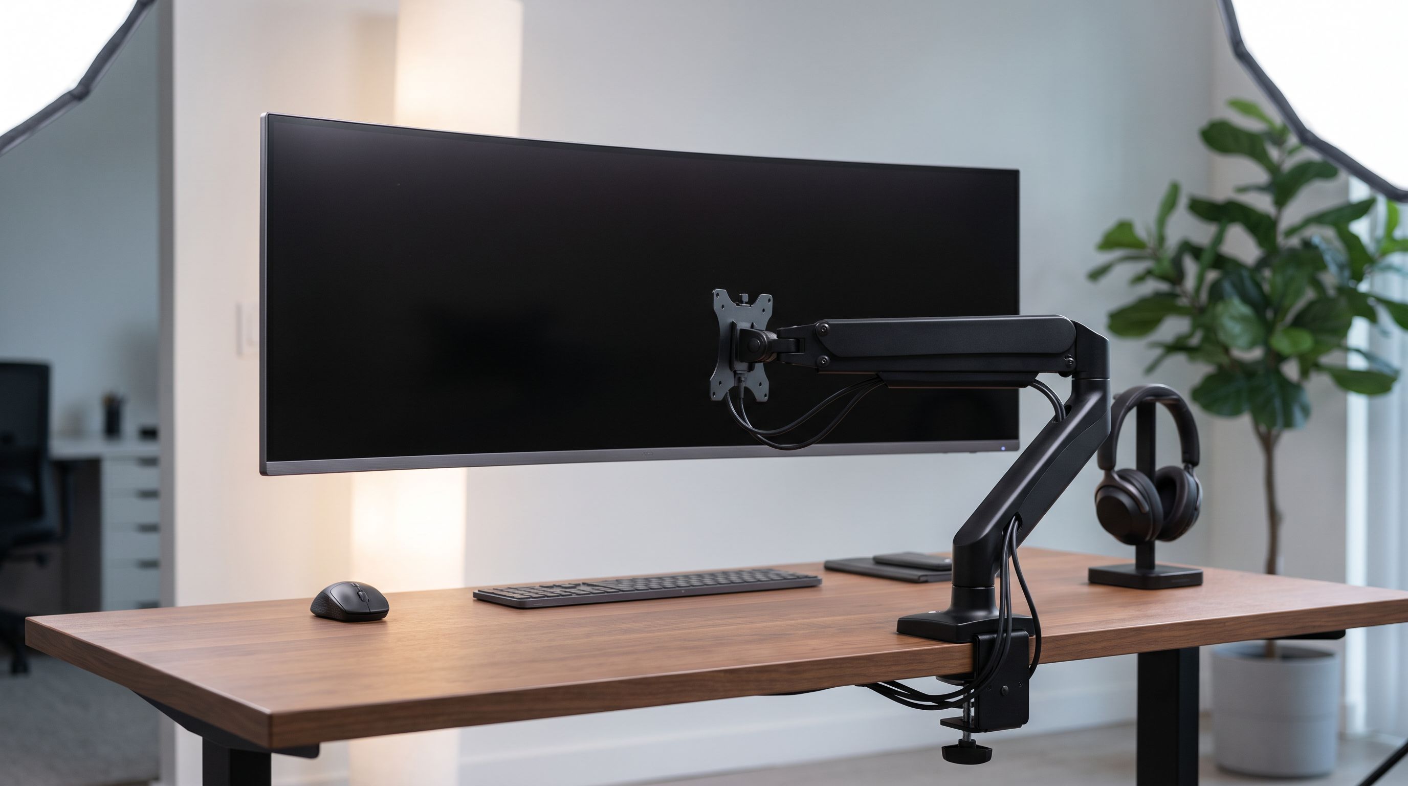 A 49-inch curved ultrawide monitor floating above a wooden desk on a heavy-duty black gas-spring monitor arm with a rear desk clamp and cable management channel